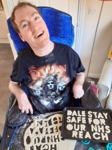 Dale at home with a sign saying stay safe to our NHS Reach