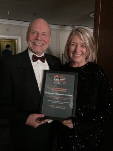 A man and woman in black tie holding a certificate