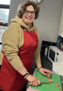 Woman smiling at the camera with chopping board and sweet potato