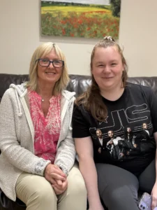 Two women sitting on sofa smiling at camera